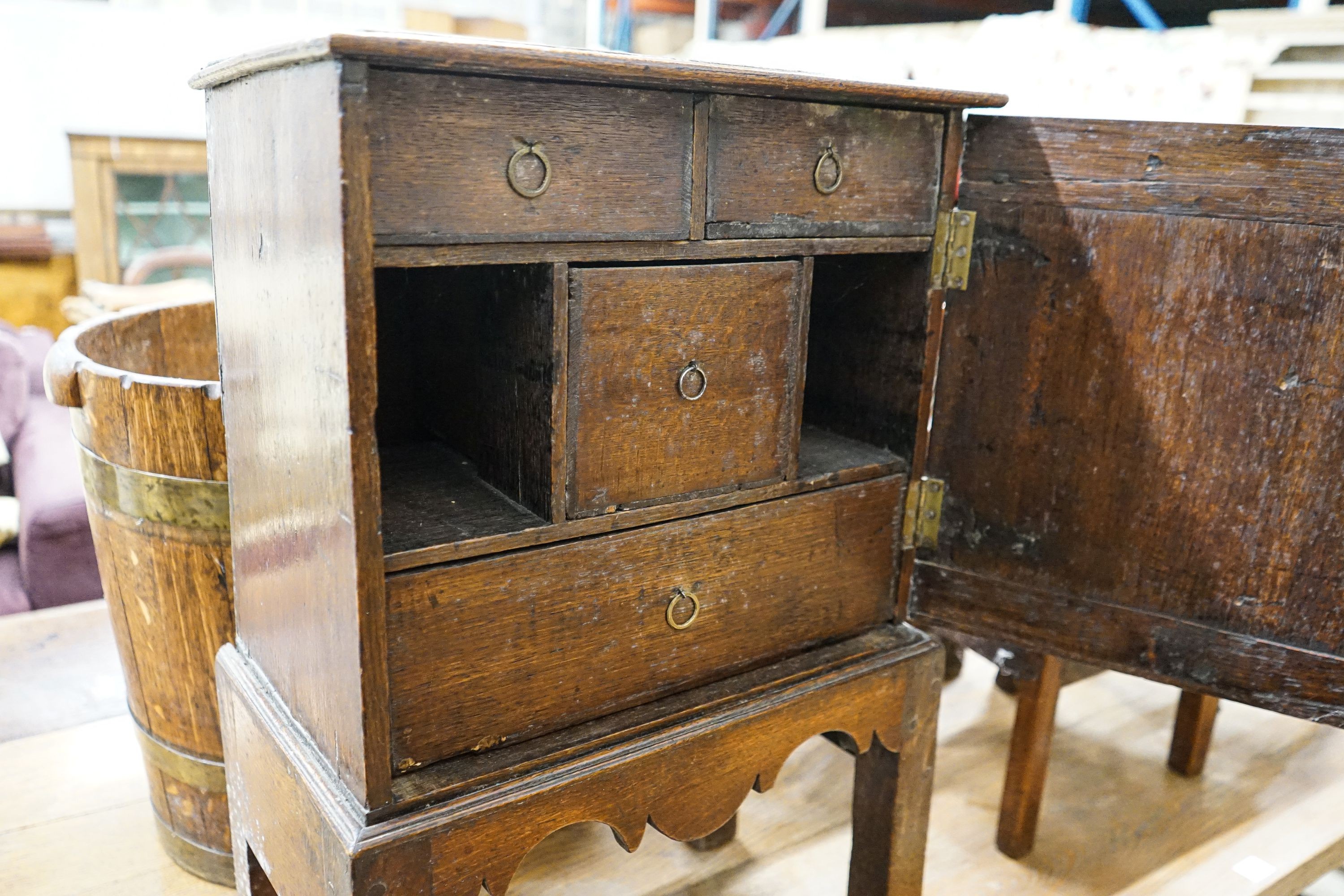 A late 17th century oak spice cupboard, with geometric panelled door enclosing five small drawers, on later stand, width 43cm, depth 27cm, height 67cm